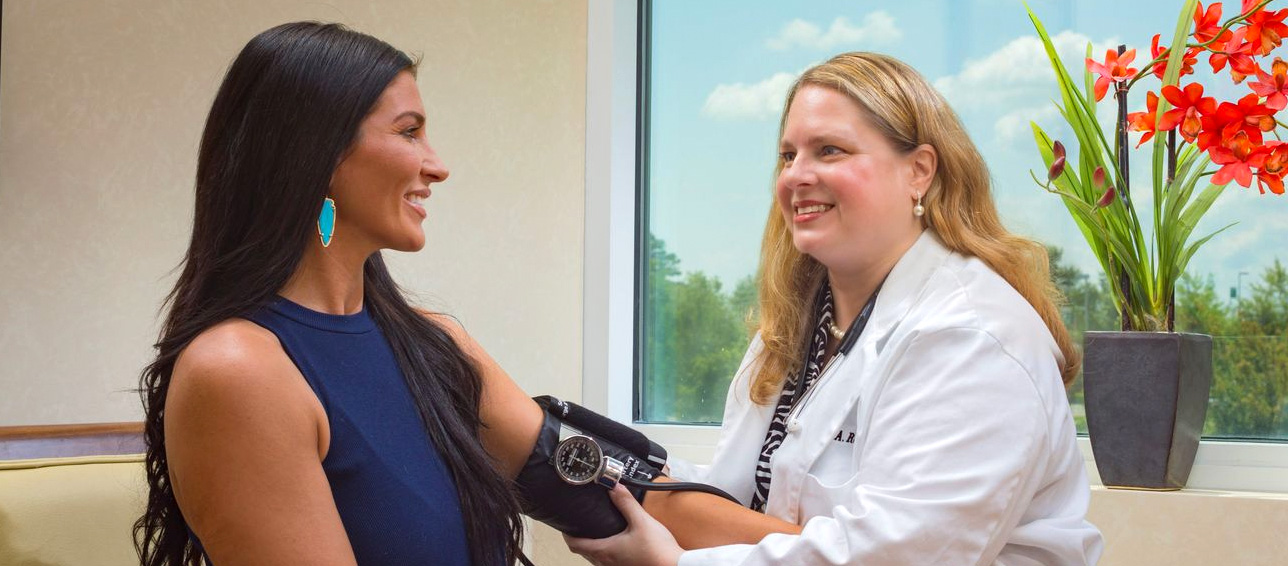 A smiling gynecologist checking a woman's blood pressure. 