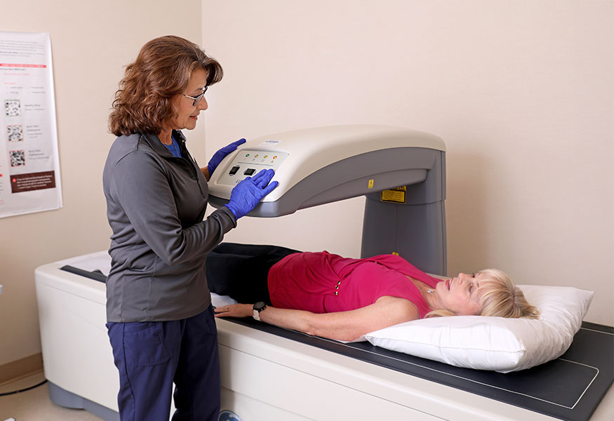 An imaging technician performing a DEXA scan on a patient.