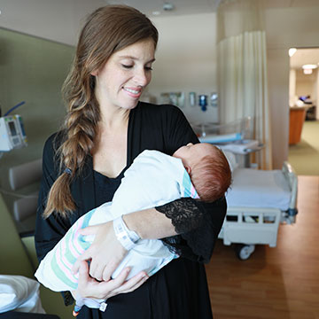 A maternity patient holding her newborn in a hospital room.