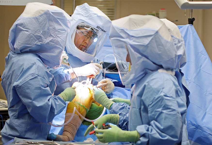 A group of surgeons performing surgery on a patient's knee.