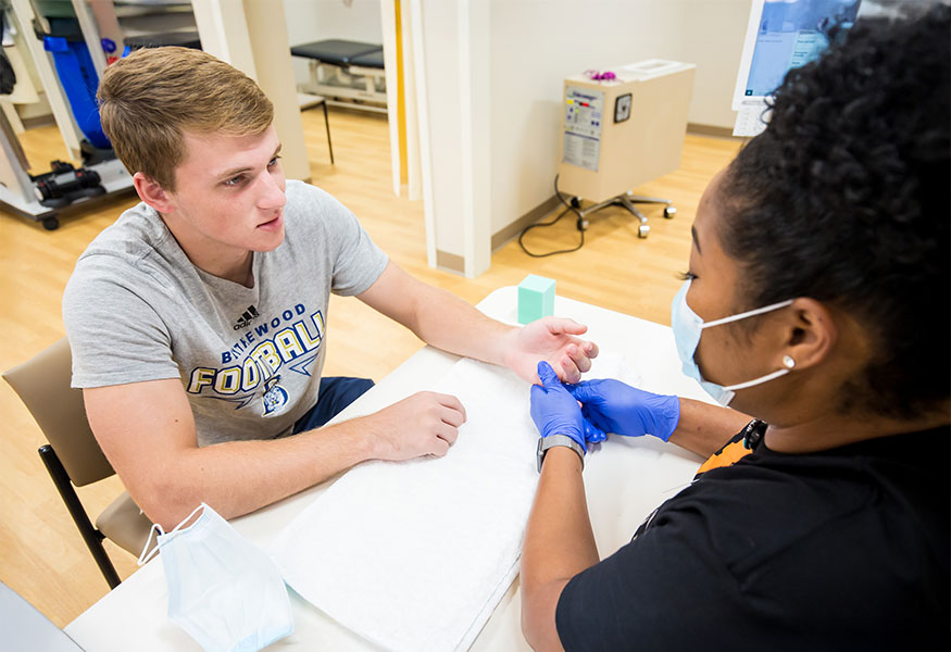 A nurse inspects a high school football player's wrist.