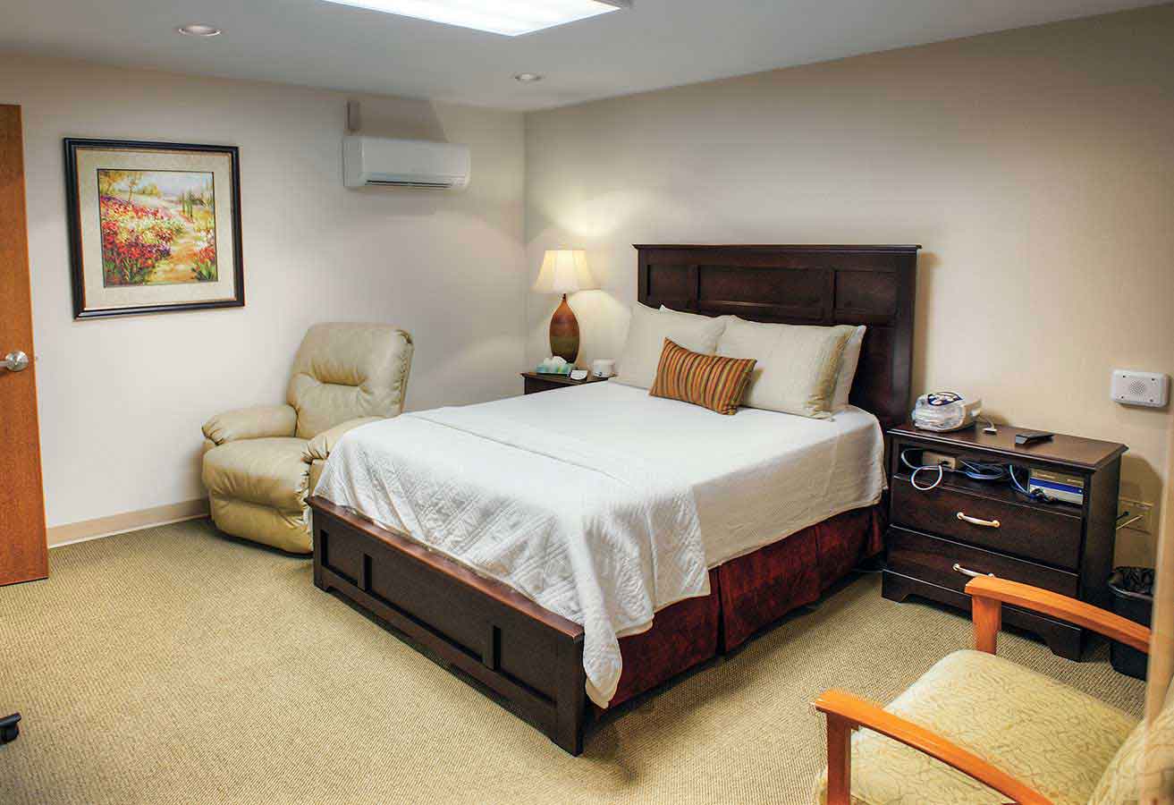 The inside of one of Lexington Health's sleep labs. There is a chair, nightstand and a freshly made bed. 